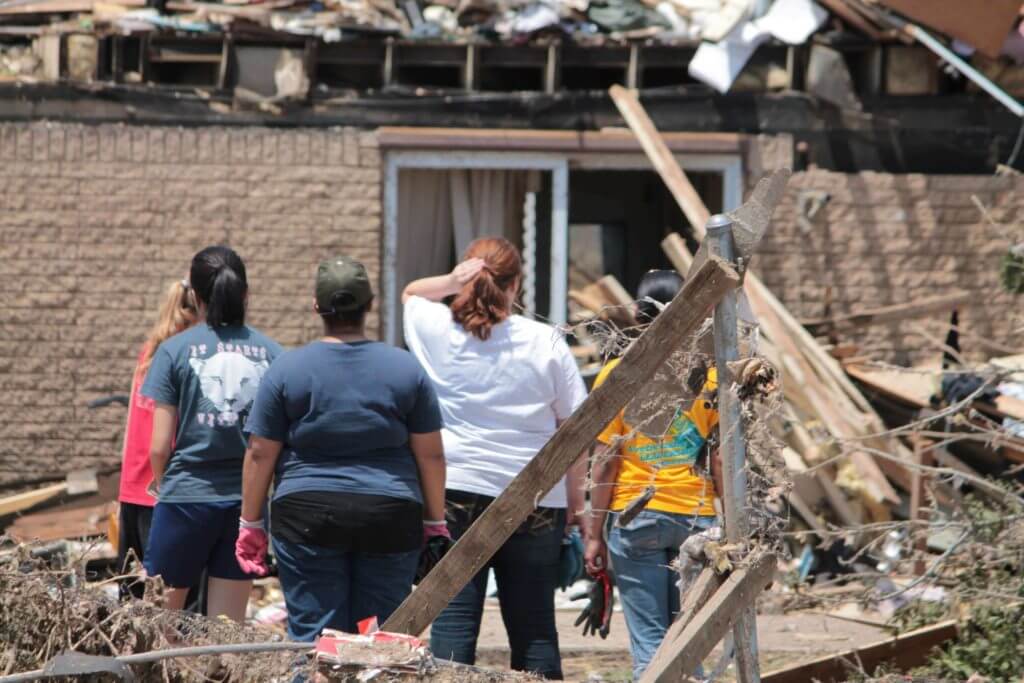Family stands in front of home damaged by Hurricane Harvey.
